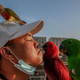 Man kissing small red parrot